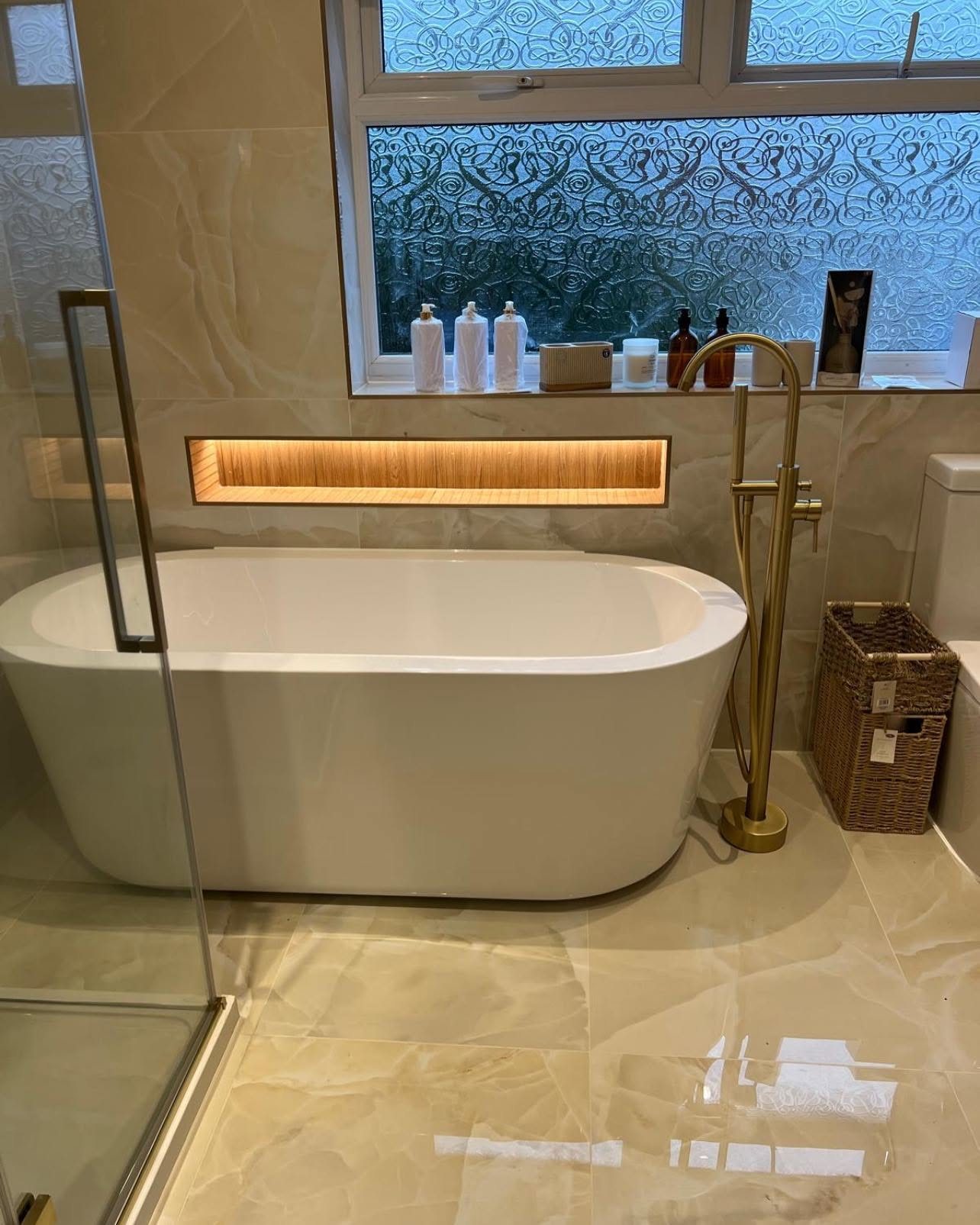Freestanding bath with gold floor tap and lit niche