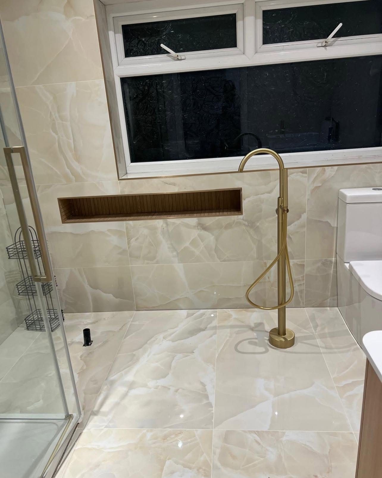Onyx-effect tiles with freestanding gold tap