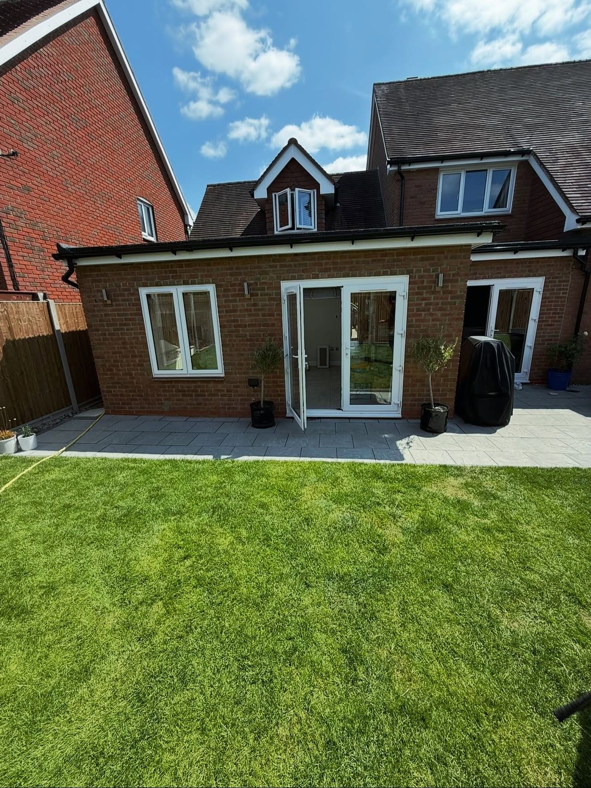 Completed brick extension exterior with patio and fresh lawn