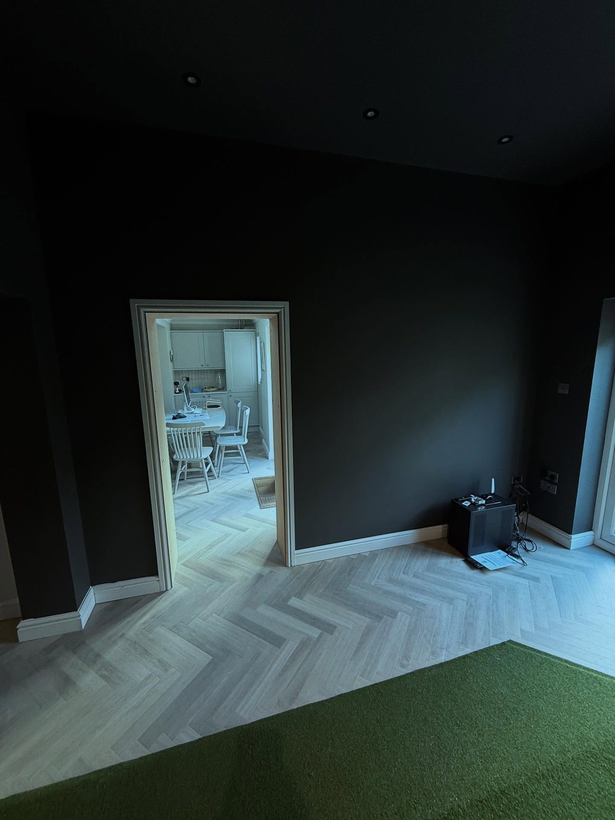 Interior with herringbone flooring meeting golf turf, dark walls