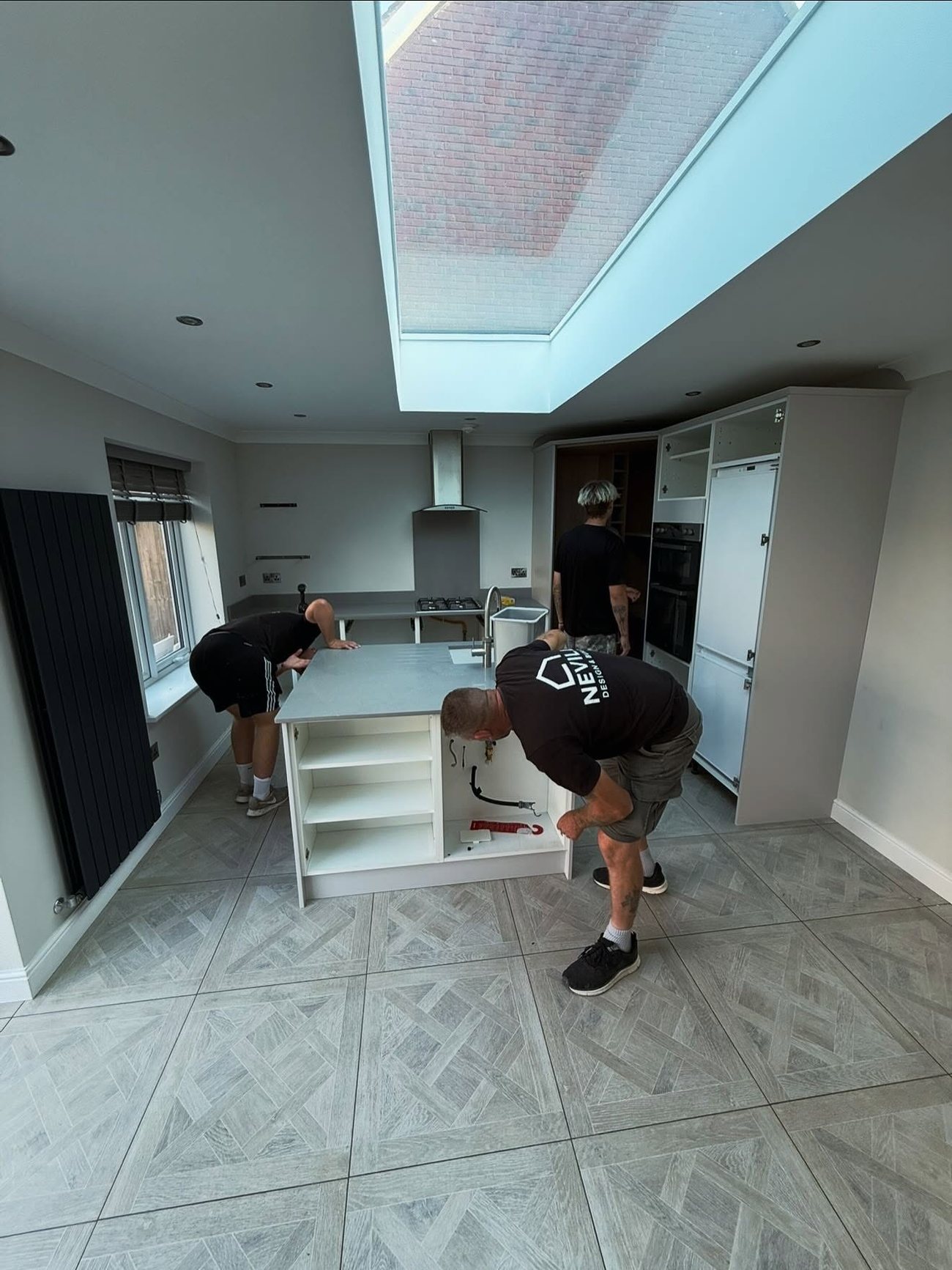 The Nevill Construction team fitting a kitchen island beneath a roof lantern